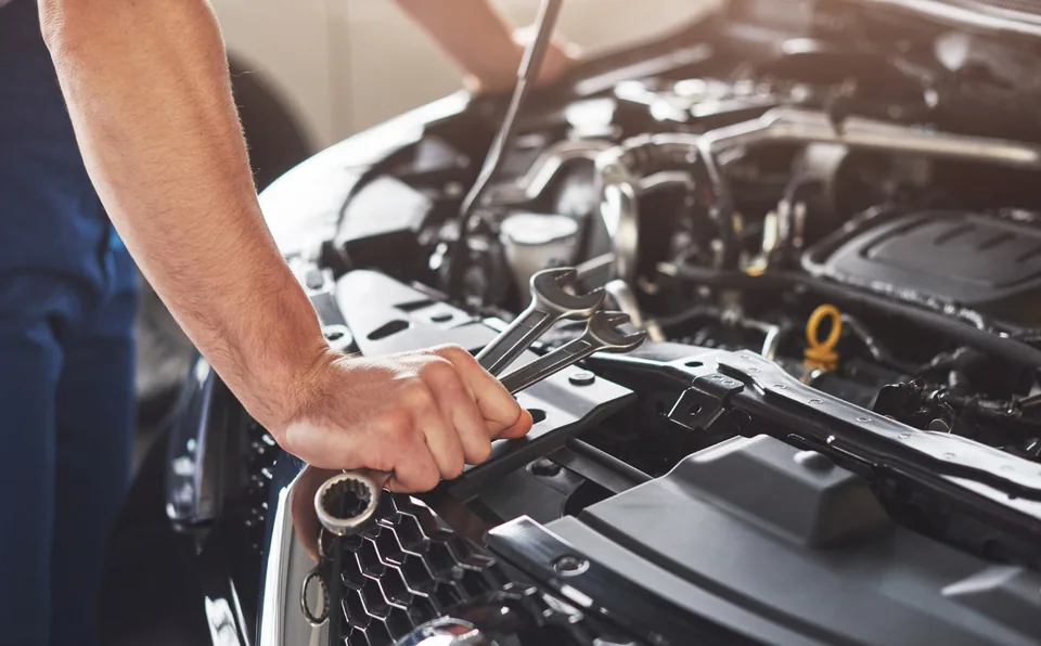 Majstor radi na motoru automobila tokom servisa klime