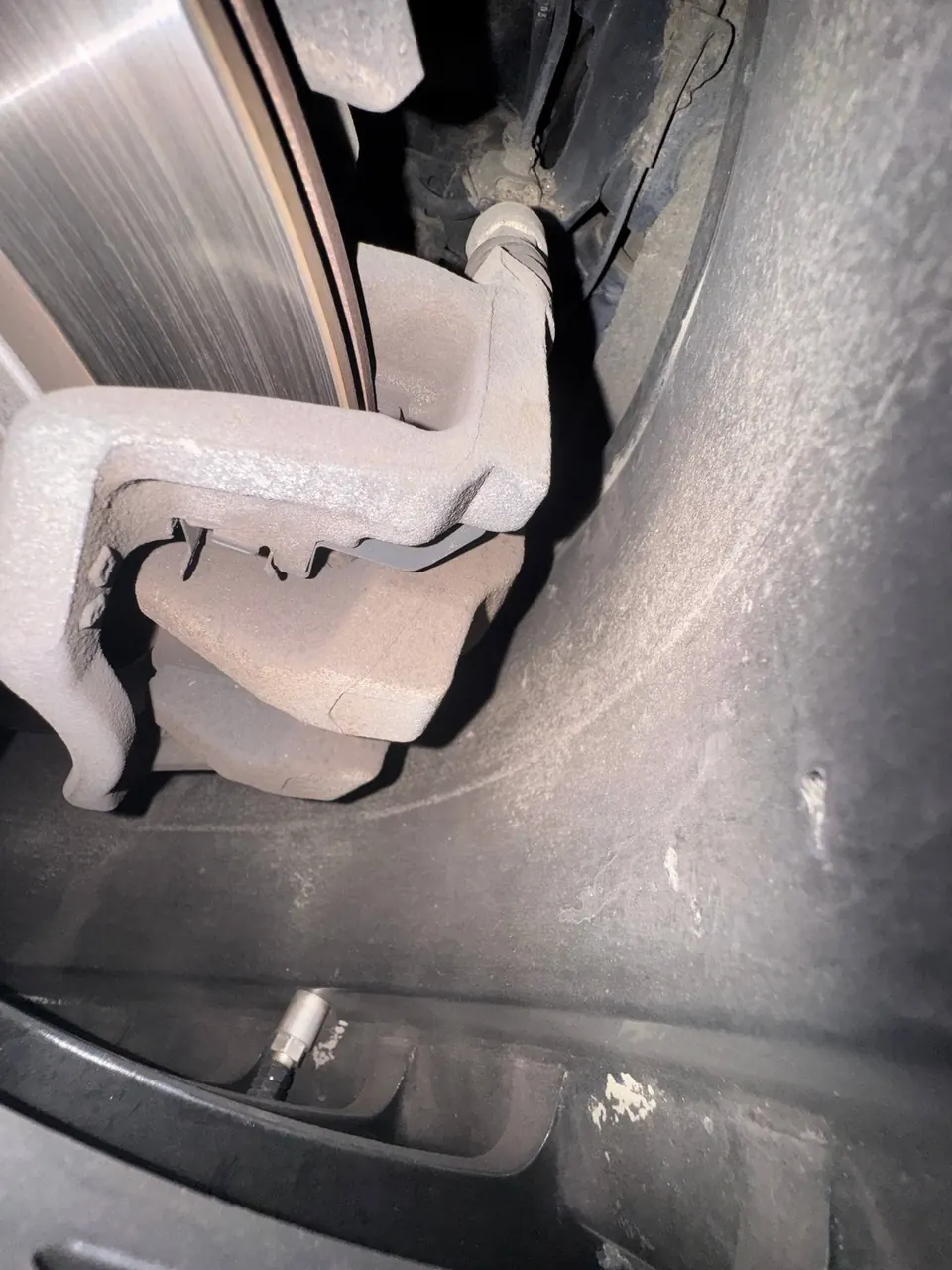 Kočioni disk i čeljust iza točka automobila u servisu