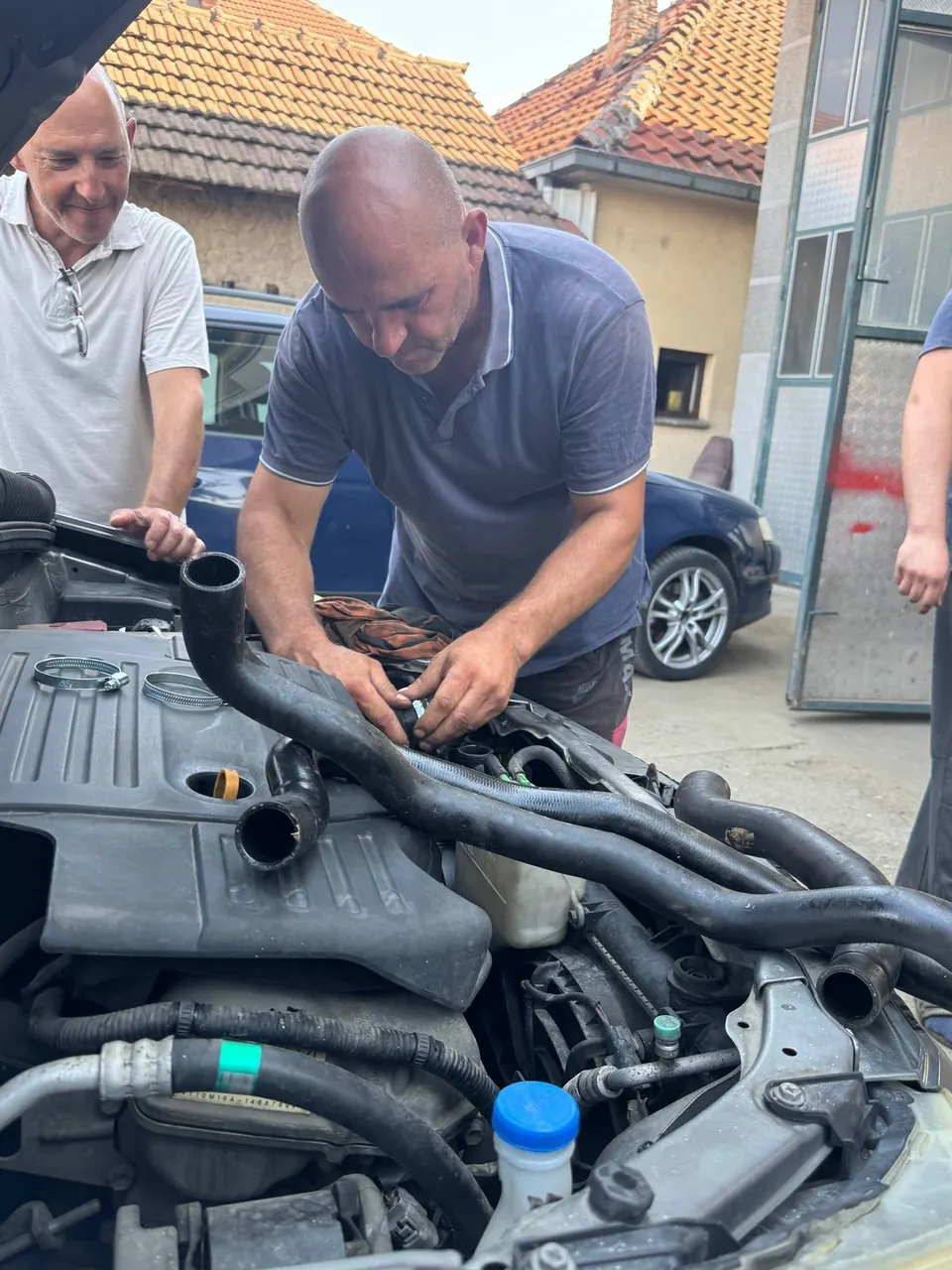 Dva majstora rade na motoru automobila u servisu