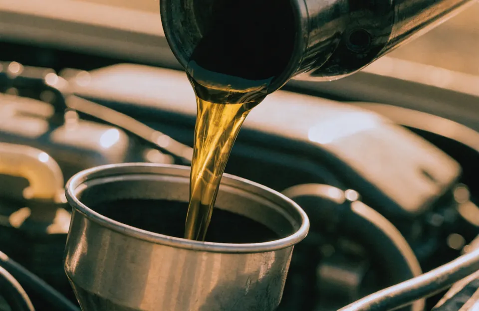 Sipanje motornog ulja kroz levak u motor automobila